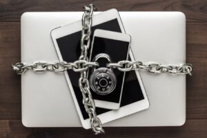 Um telefone, tablet e laptop acorrentado e trancados.