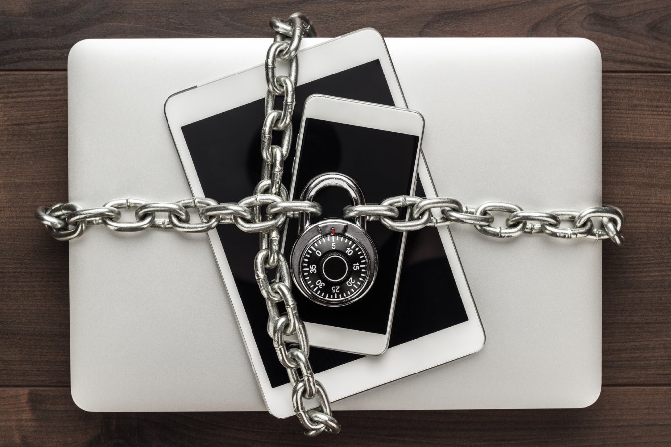 Um telefone, tablet e laptop acorrentado e trancados.