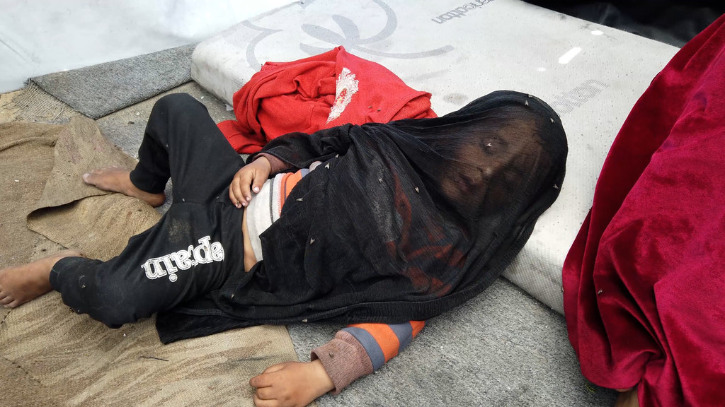 Moscas pairam sobre um filho adormecido da família Abu ASR em sua barraca em Gaza.