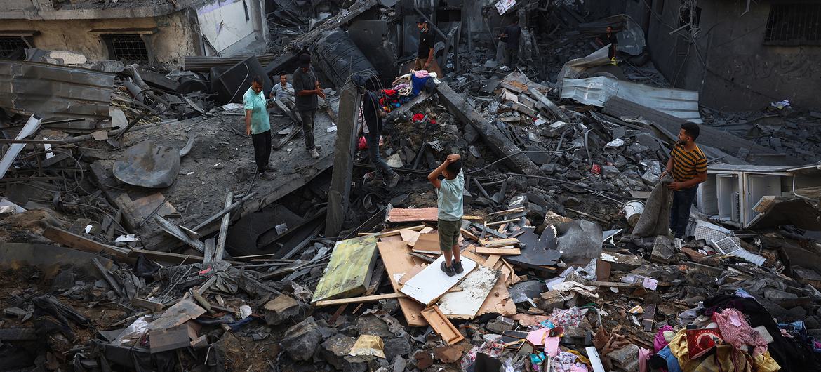 As pessoas procuram os escombros de um edifício destruído na faixa central de Gaza.