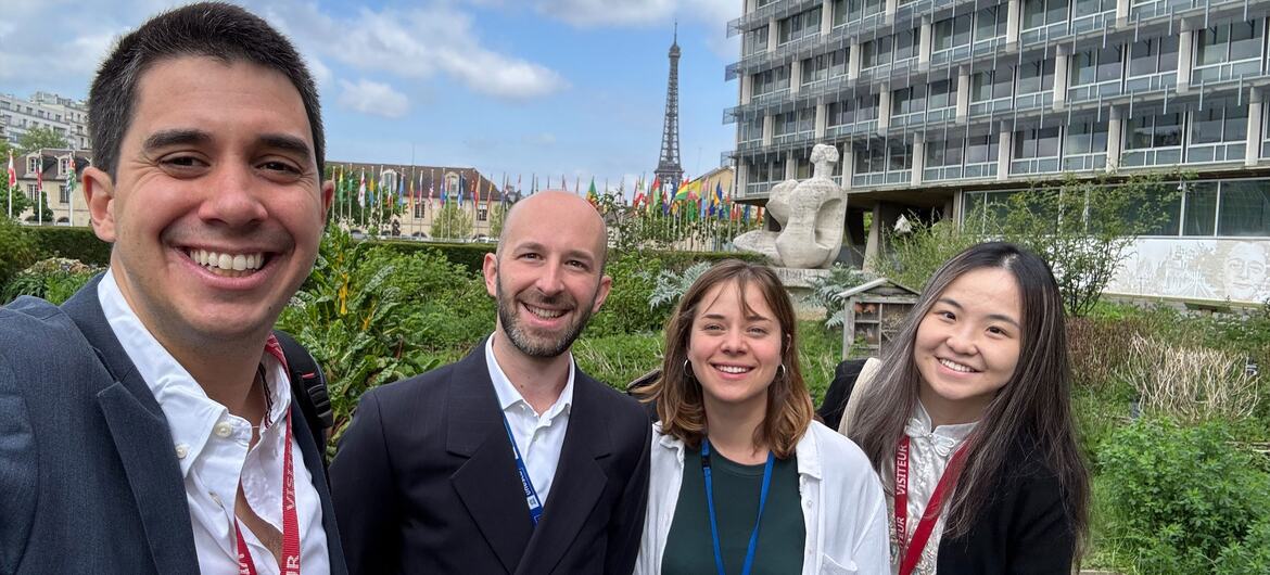 ASG Felipe Paullier e Romain Parlier com jovens em Beirute, ao ar livre perto da Torre Eiffel e de um edifício moderno, sorrindo para uma foto.