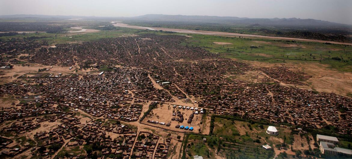 Vista aérea da cidade de Zalingei, no centro de Darfur, Sudão, mostrando um extenso assentamento com edifícios de tijolos de barro, cercado por terras áridas e um rio à distância, capturada em 18 de setembro de 2013.