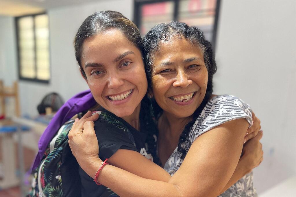 Katerine Avella e Lina Garcés sorrindo e se abraçando após concluir um curso de confecção no ETCR de Caño Indio, na Colômbia, que deu origem à criação das saias da marca Ixora.